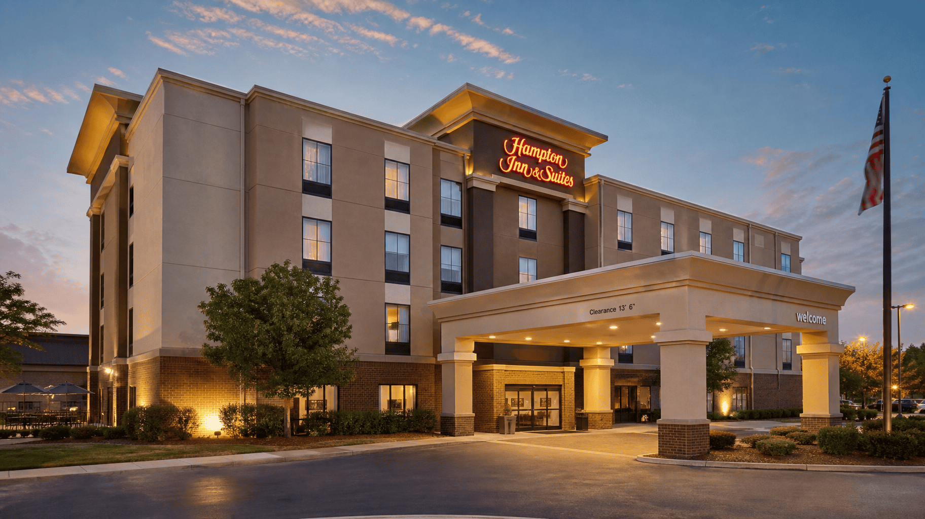 Exterior of a well-kept select-service hotel at dusk, warm lighting